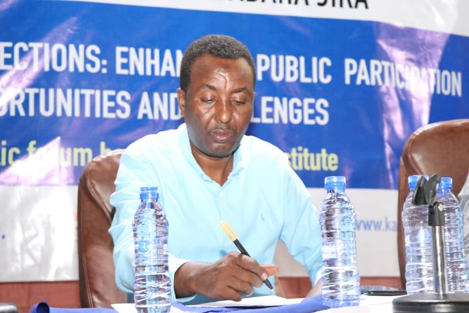 The moderator taking notes beneath the forum banner reading Puntland Local Elections: Enhancing Public Participation